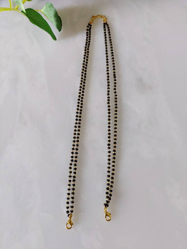 18-inch mangalsutra string with black beads and gold-tone clasps, showcased on a white background with green leaves in the image.