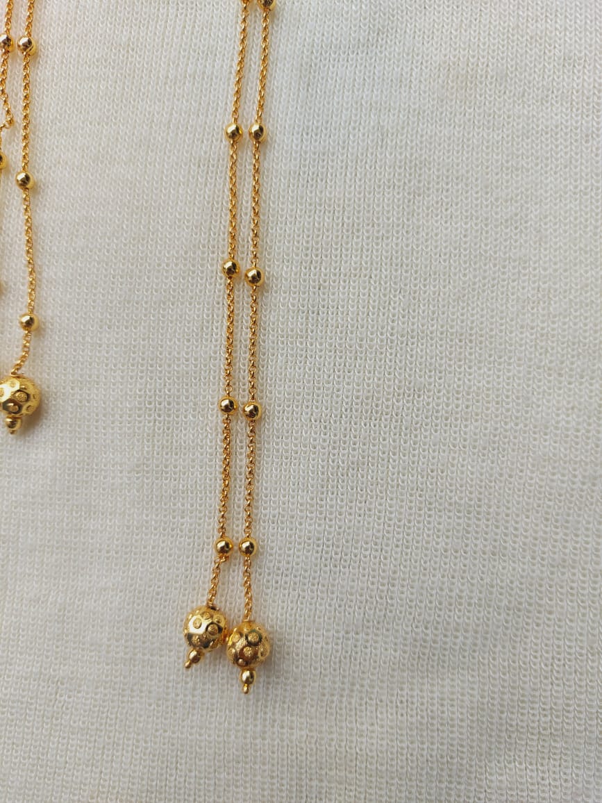 Delicate golden mundavali with intricate bead detailing, displayed on a neutral knitted background at Mugdha Jewellery Store.