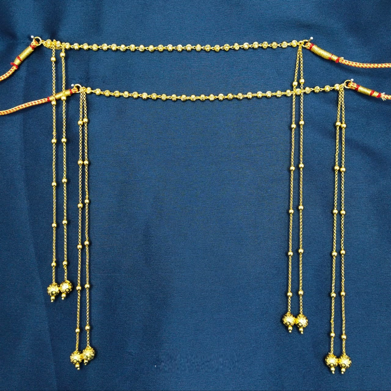 Delicate and Elegant Golden Mundavali - Ornate gold-toned necklace with intricate beads and hanging floral pendants displayed against a navy blue background.