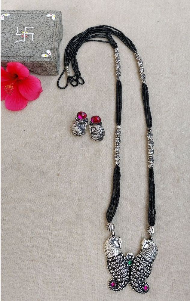 Oxidized Silver Mangalsutra with Butterfly Pendant and Studs
Ornate silver-tone mangalsutra necklace with a central butterfly-shaped pendant, accented by rhinestones. Matching stud earrings complete the elegant jewelry set.