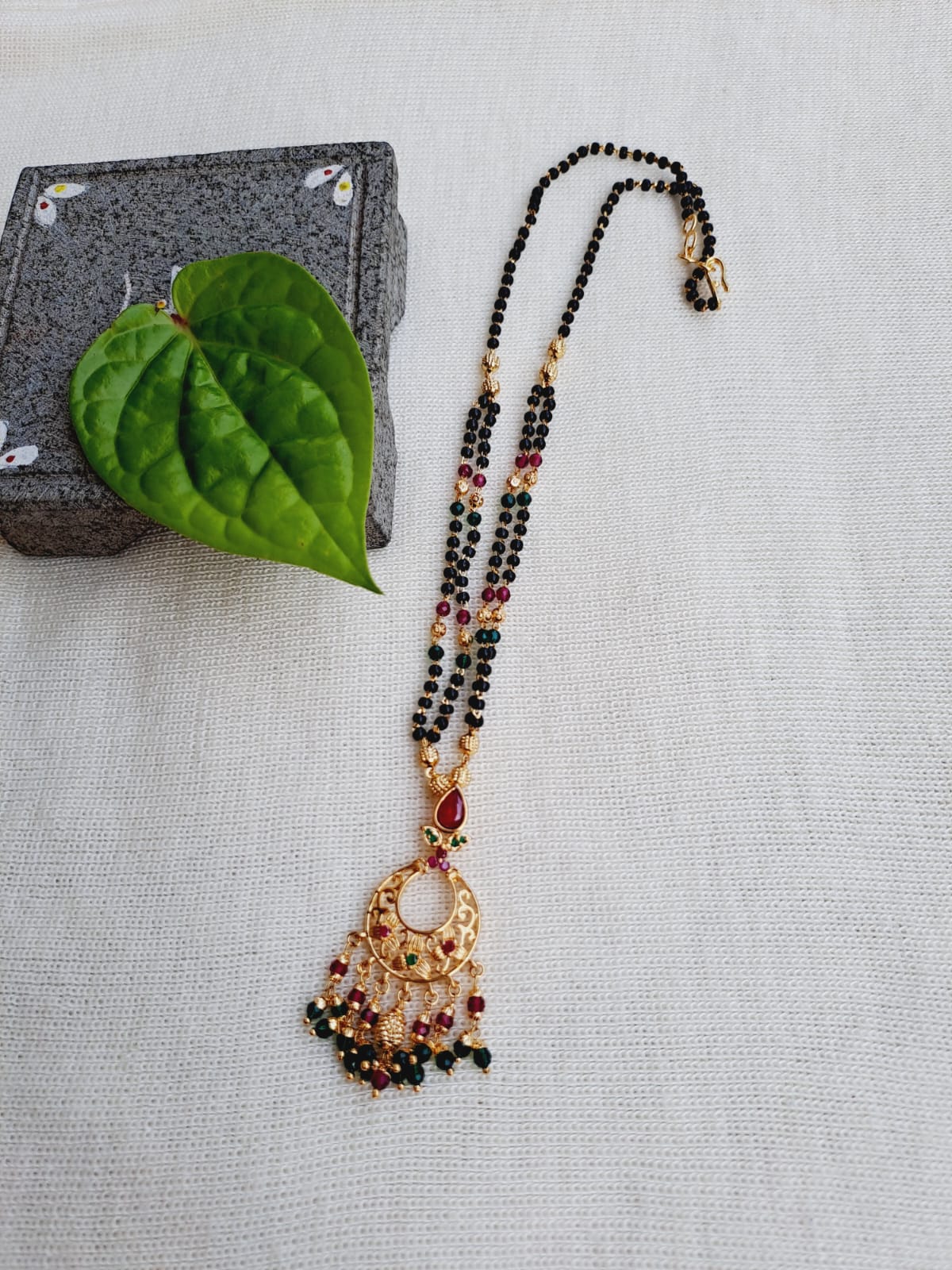 Decorative floral mangalsutra necklace with gemstones on a light background