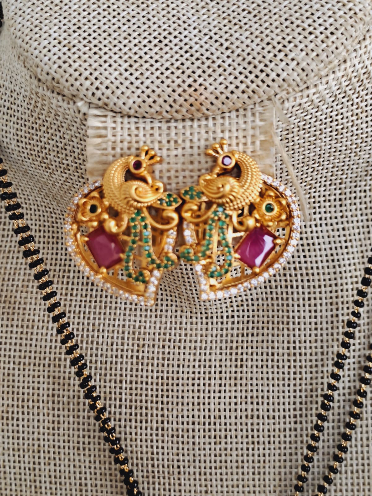 Intricately crafted golden peacock short mangalsutra with colorful gemstone accents, suspended on a delicate chain necklace.