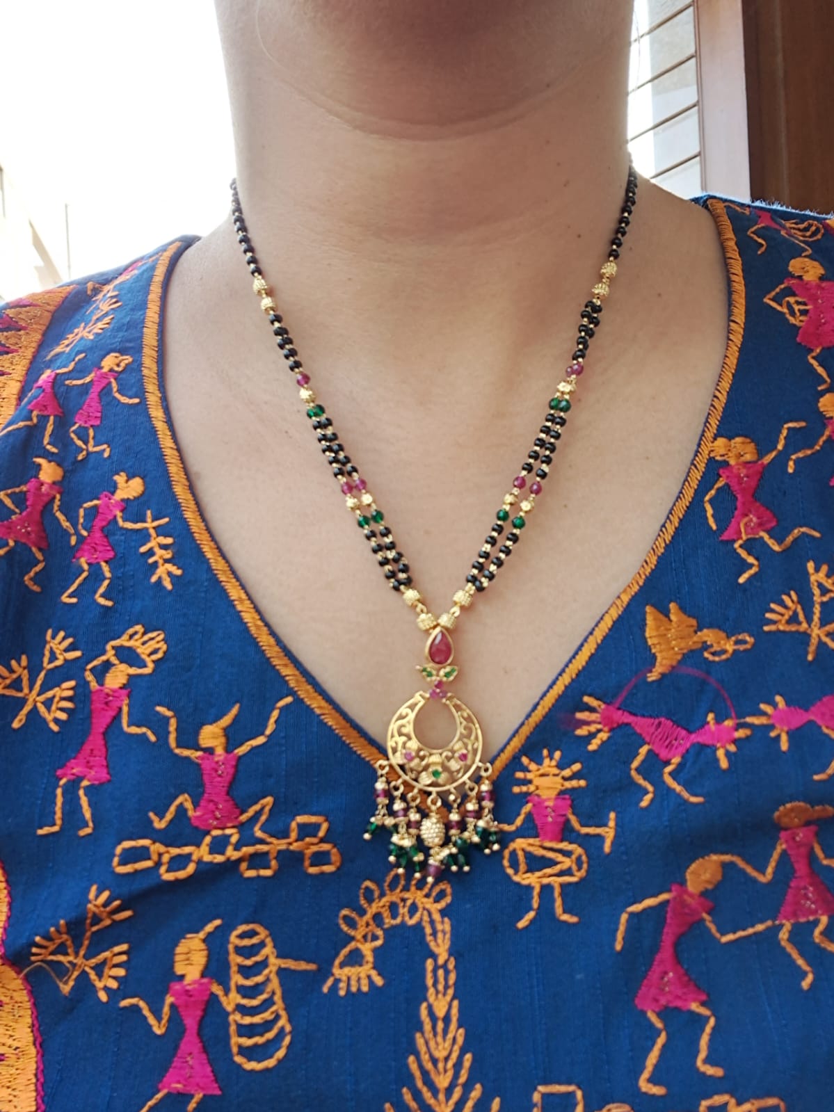 Elegant designer short flower stone mangalsutra with colorful beaded pendant on a blue embroidered ethnic blouse.