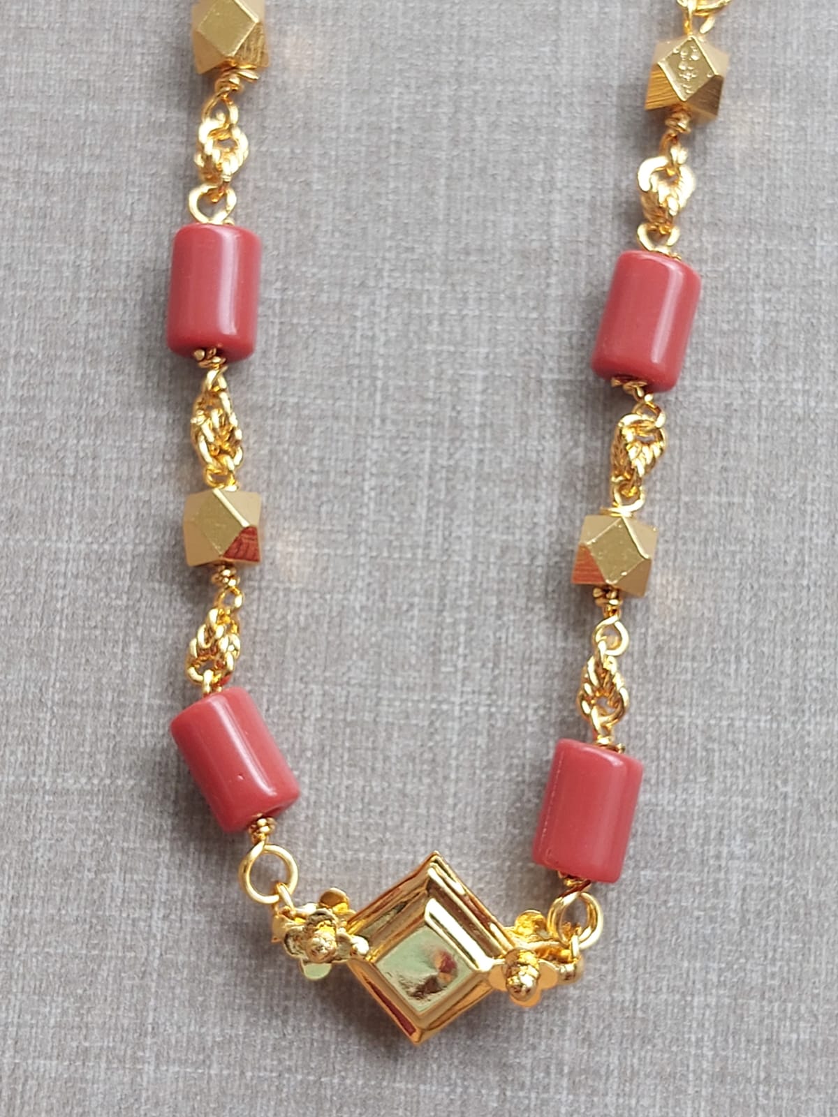 Elegant gold-tone necklace with red beads and geometric pendant