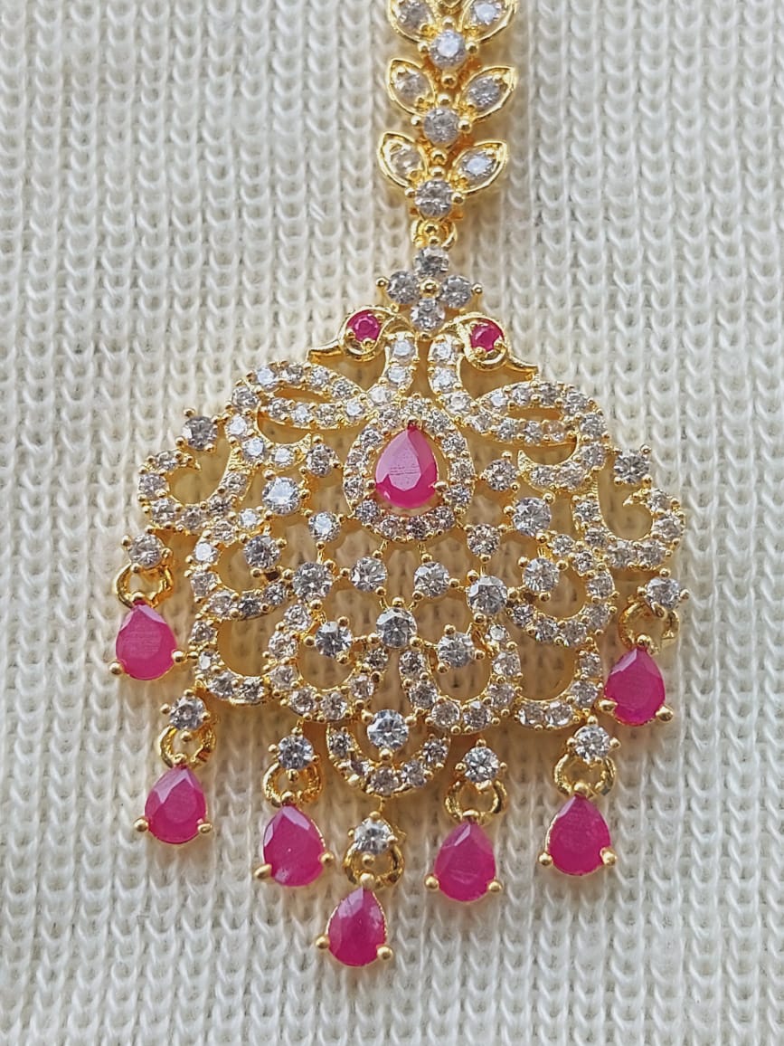Elegant gold-toned maang tika adorned with sparkling diamonds and vibrant pink gemstones, creating a regal and eye-catching headpiece accessory.