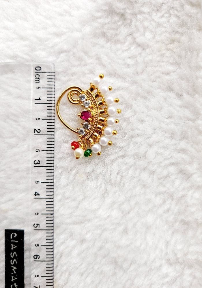 Ornate gold pendant with colorful gemstones on fluffy white background