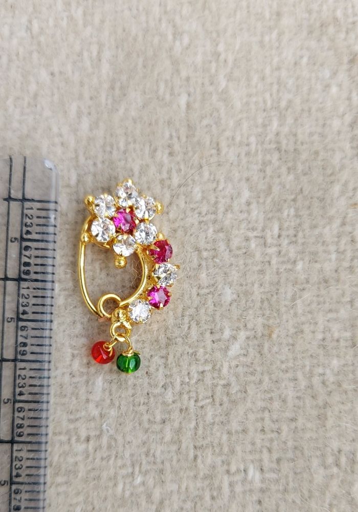 Small Elegant Floral Nose Ring
Ornate gold-tone nose ring with colorful gemstone floral design, displayed on a plain white background.