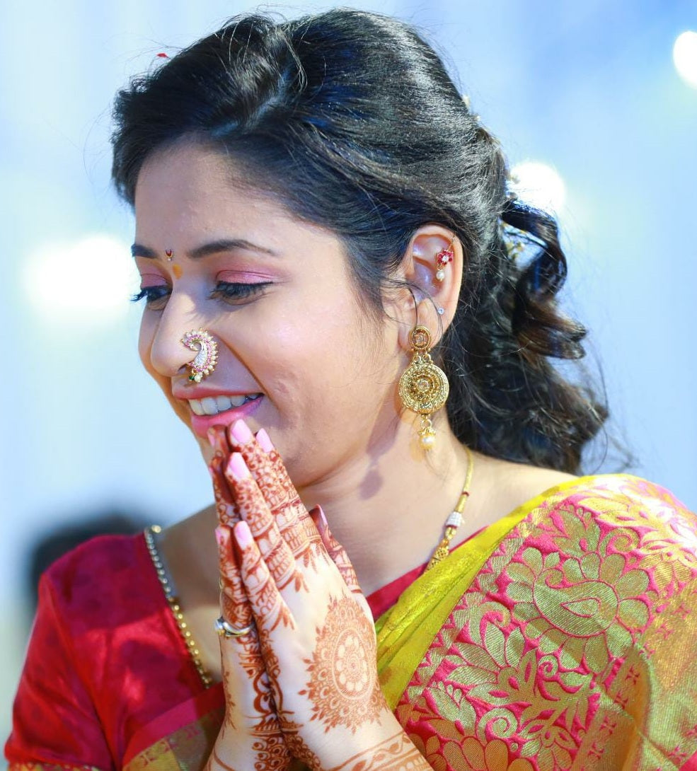 Ornate peacock-inspired nose ring, delicate henna-decorated hand, and vibrant traditional Indian attire in the image.