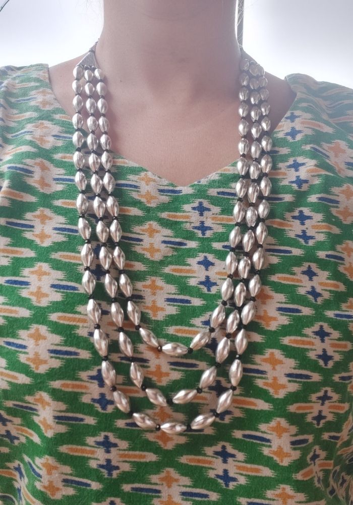 Intricate Oxidized Silver Dholki Bead Necklace
This image shows an intricate long necklace with multiple strands of oxidized silver dholki beads, giving it a unique and stylish appearance. The necklace is displayed against a vibrant patterned fabric background, creating a visually appealing contrast.