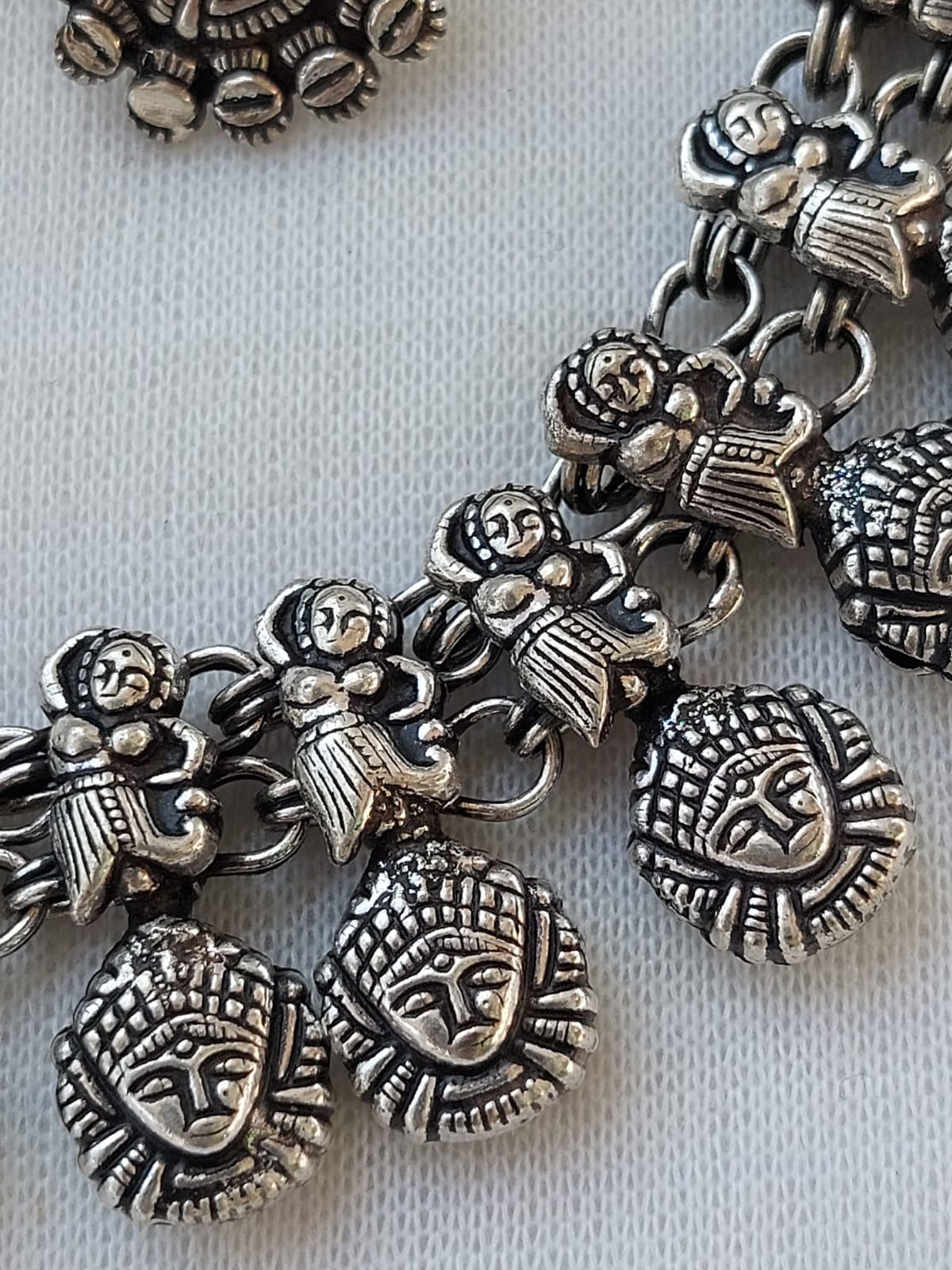 Oxidised Necklace Set with intricate ethnic metal charms and pendants displayed on a gray fabric background.