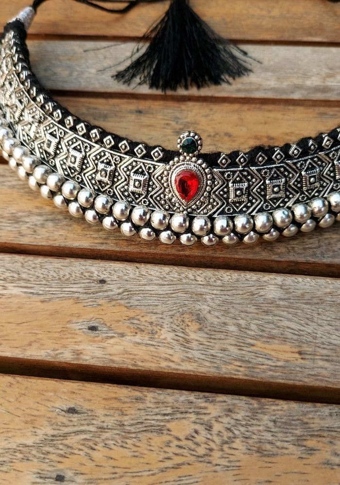 Stunning traditional oxidised peshwai vajrateek necklace with intricate embroidered design and red gemstone focal point, displayed on wooden background from Mugdha Jewellery Store.