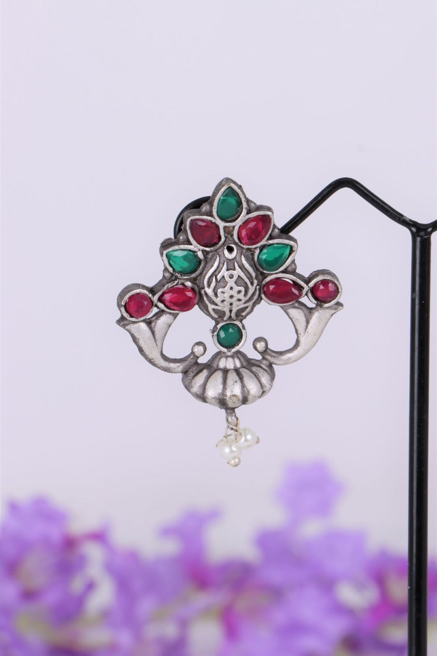 Multicolour Designer Oxidised Earrings - Elegant floral-shaped oxidized silver earrings with colourful gemstones including ruby, emerald, and pearl, displayed against a blurred purple floral background.