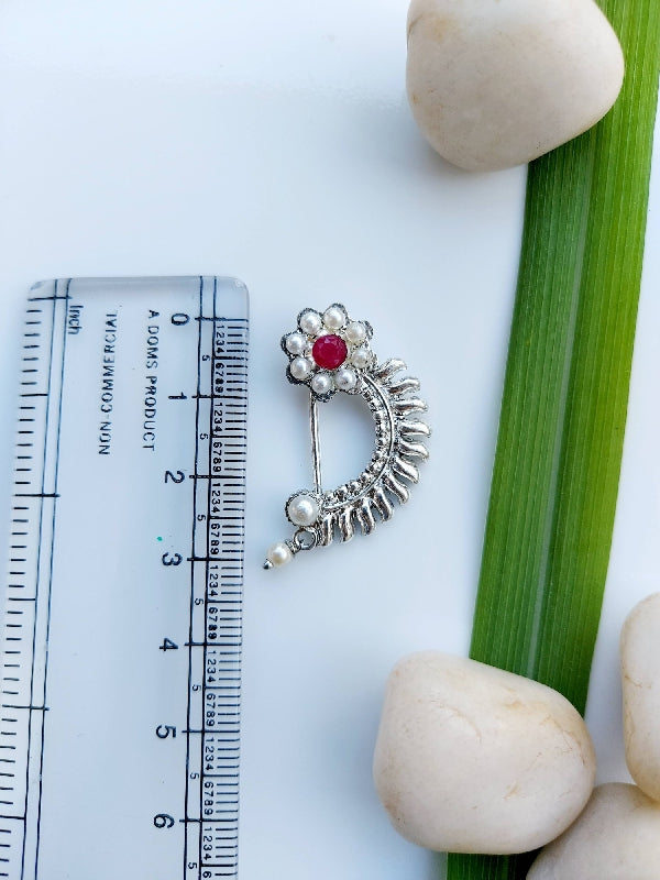 Elegant pearl flower oxidised nath on measurement ruler surrounded by natural stones