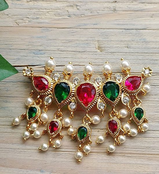 Elegant gold-toned pendant with vibrant gemstones and pearls, displayed on a rustic wooden surface.