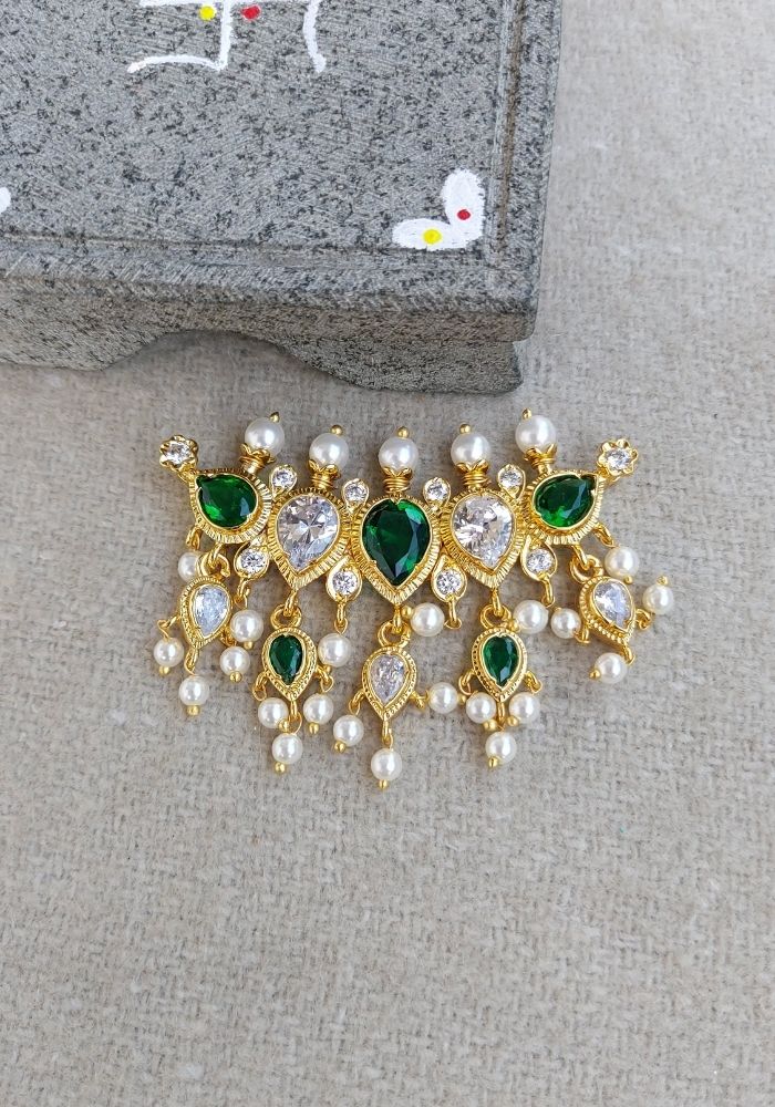 Green and gold AD pendant with emerald-like stones and pearls, displayed on a gray background.
