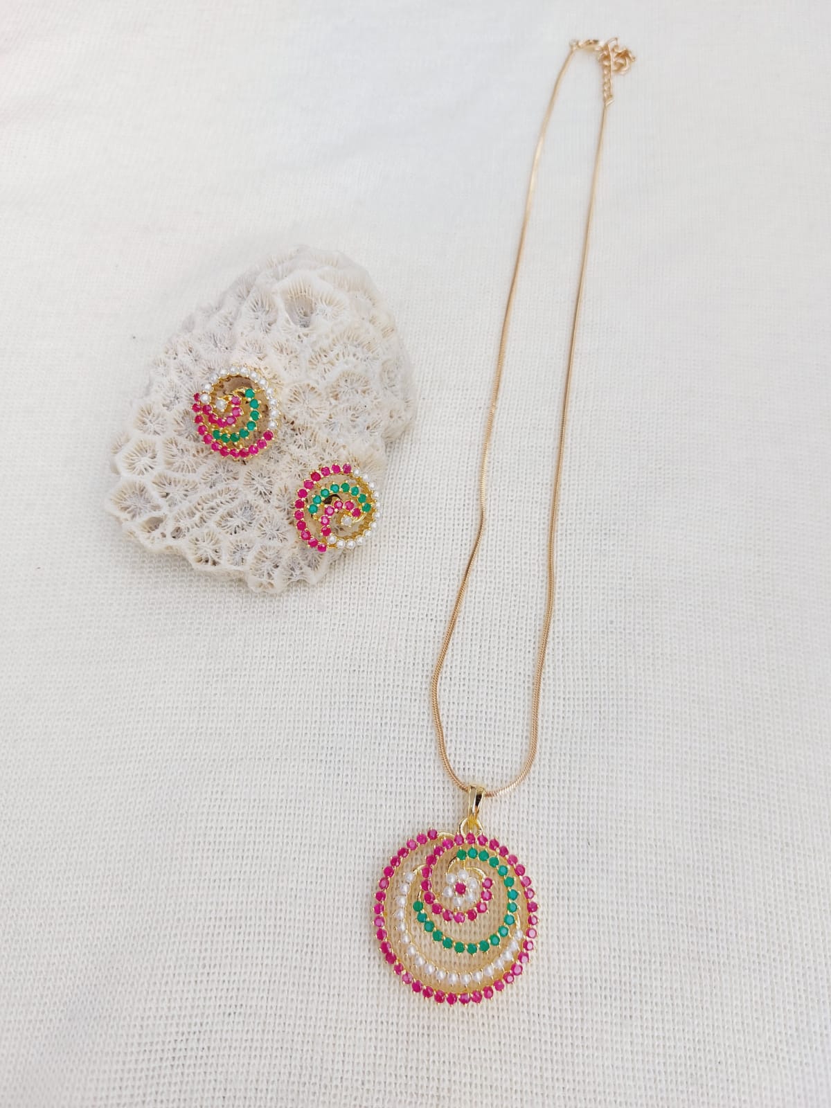 Elegant multicolored pendant set with delicate gold chain on white background
