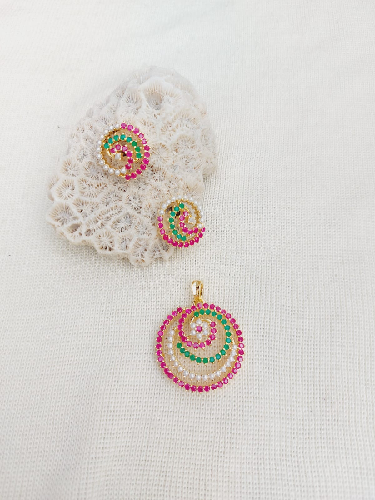 Colorful Spiral Pendant Necklace Set - Vibrant gemstone accents on a delicate gold-toned pendant and matching earrings displayed on a soft white fabric background.