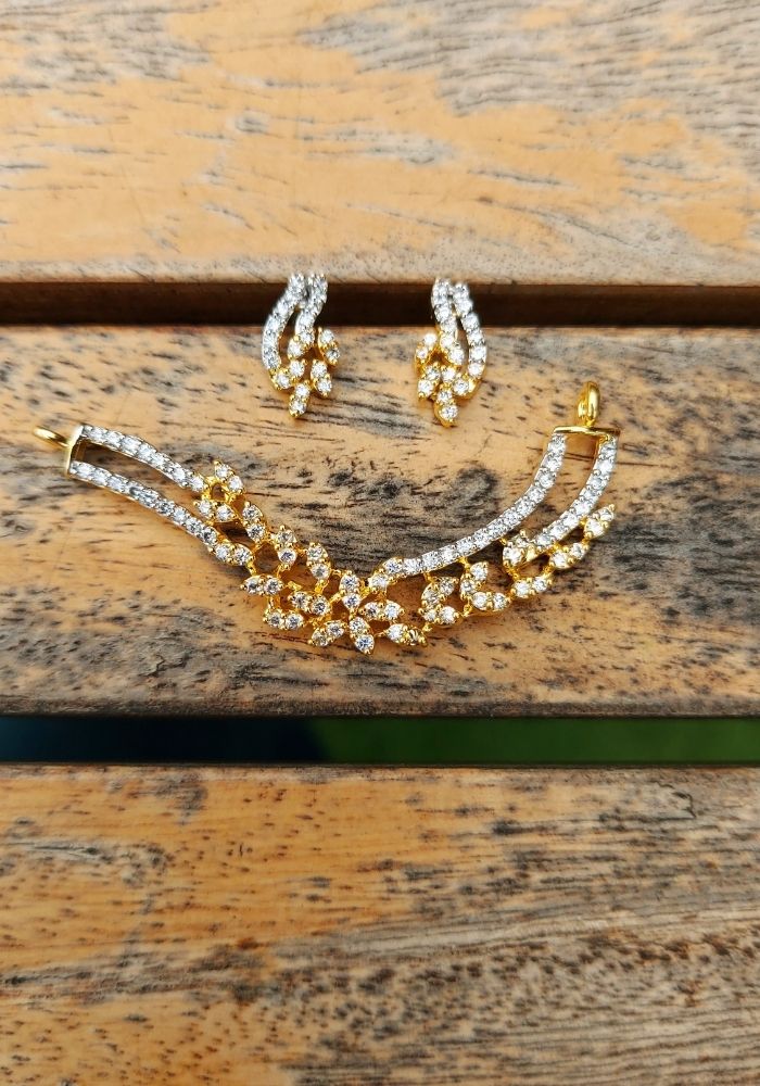 Elegant American diamond set with golden accents, featuring a necklace and matching earrings showcased on a rustic wooden surface.