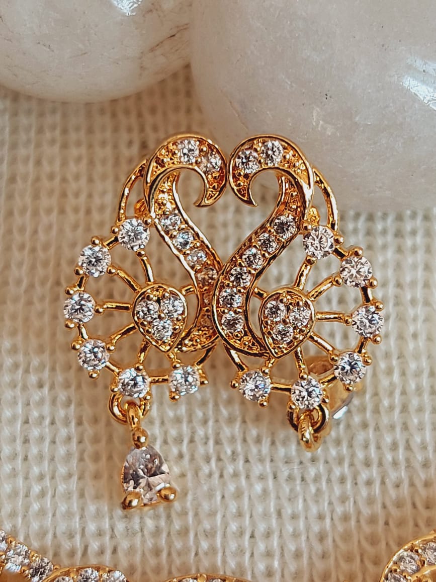 Ornate gold and crystal jewelry piece featuring intricate floral and heart-shaped designs, adorned with sparkling gemstones, showcased on a light-colored knitted background.