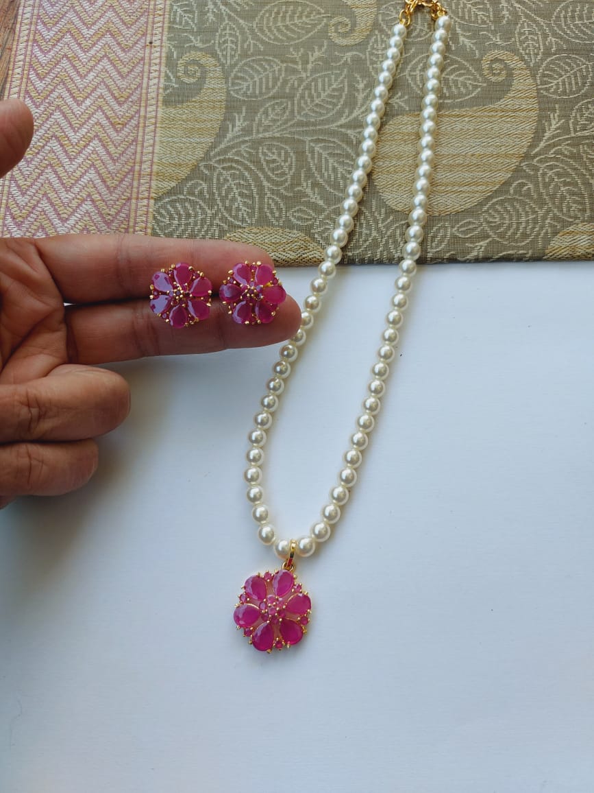 Elegant pearl necklace and earrings set with vibrant pink floral accents from Mugdha Jewellery Store
