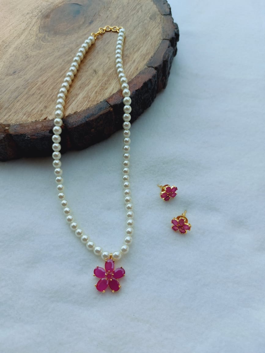 Elegant Pearl Flower Necklace Set - Pearls, Ruby Flower Pendant, and Matching Earrings on Wooden Background