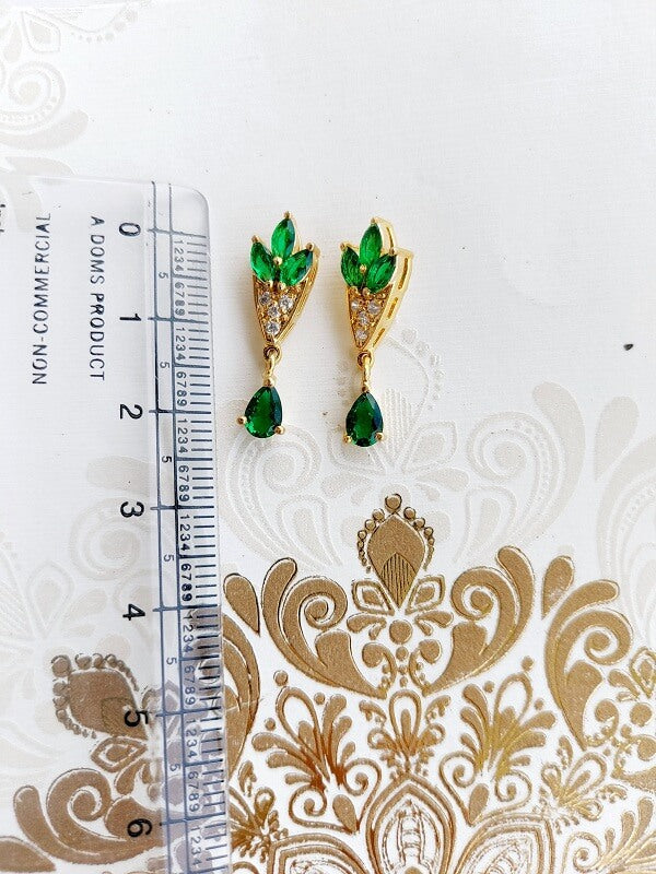 Green Stone Flower Basket Earrings, Mugdha Jewellery Store. Elegant gold-toned earrings with intricate floral pattern and green gemstone accents.