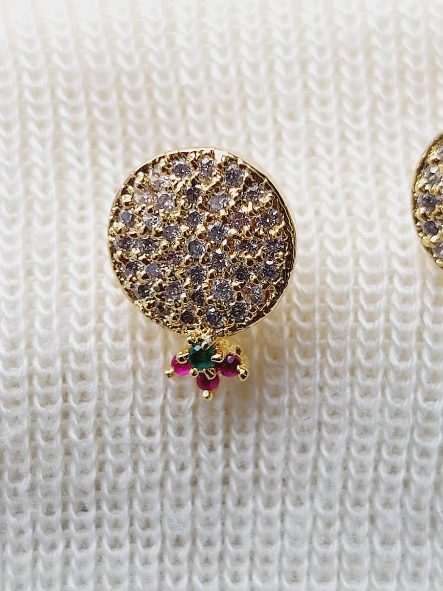 Sparkly round earrings with multicoloured stones, placed on a textured white background