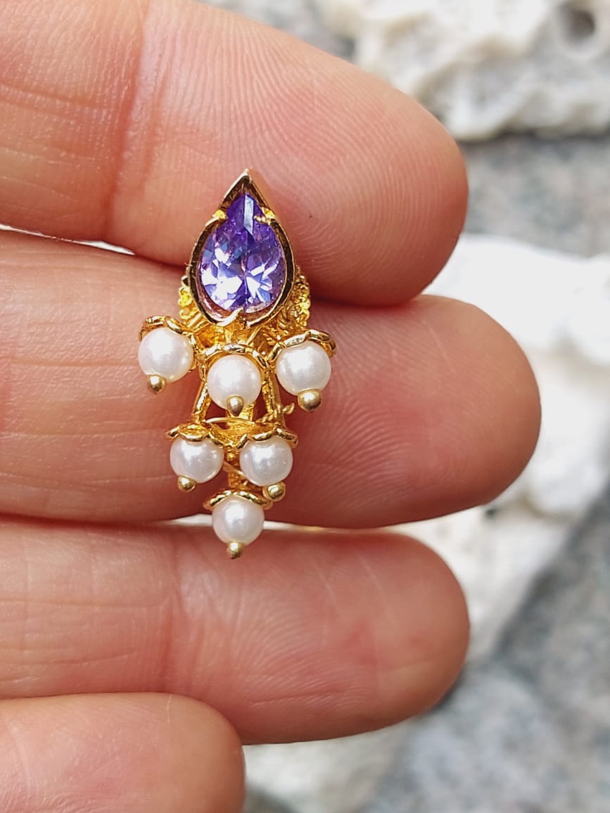 Elegant violet teardrop pendant with pearl accents, displayed on a human hand against a light background