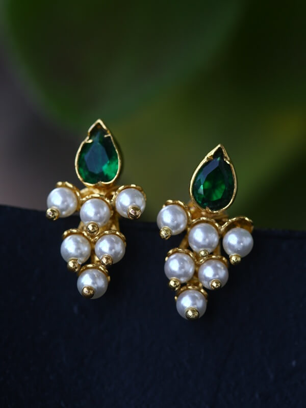 Elegant gold-toned earrings with lustrous pearl clusters and vibrant green gemstone accents, showcased against a dark background.