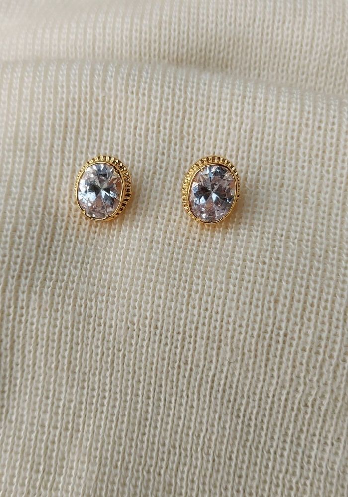 Elegant white stone stud earrings from Mugdha Jewellery Store featuring a round-cut crystal gem in a golden setting.