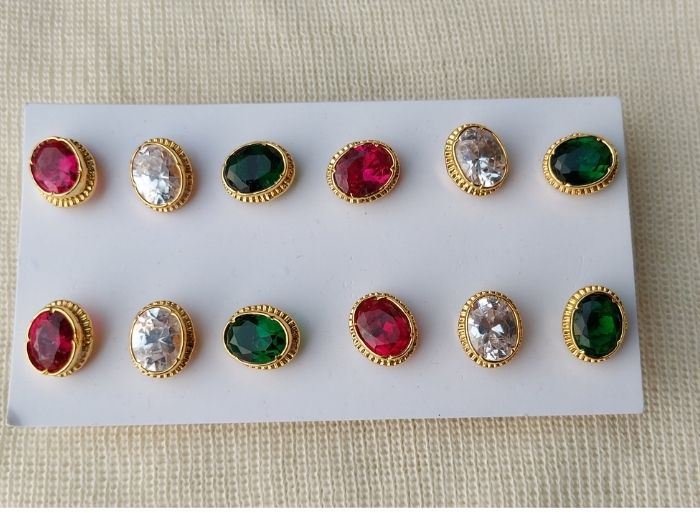 Elegant gold-framed gemstone stud earrings featuring vibrant red, green, and clear stones displayed on a neutral background.