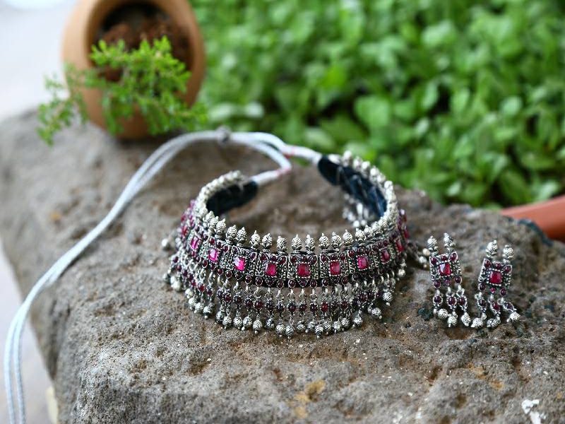 Silver Copper Mixed Laffa: Intricate silver and copper necklace with vibrant pink gemstones, displayed against a verdant natural backdrop.