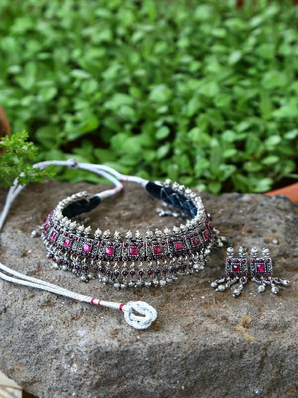 Silver and copper mixed laffa necklace and earring set with vibrant pink gemstones on a natural stone background.