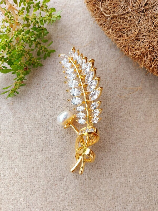 Elegant gold-tone feather-shaped brooch adorned with sparkling white stones and a delicate pearl accent, capturing the essence of nature's beauty.