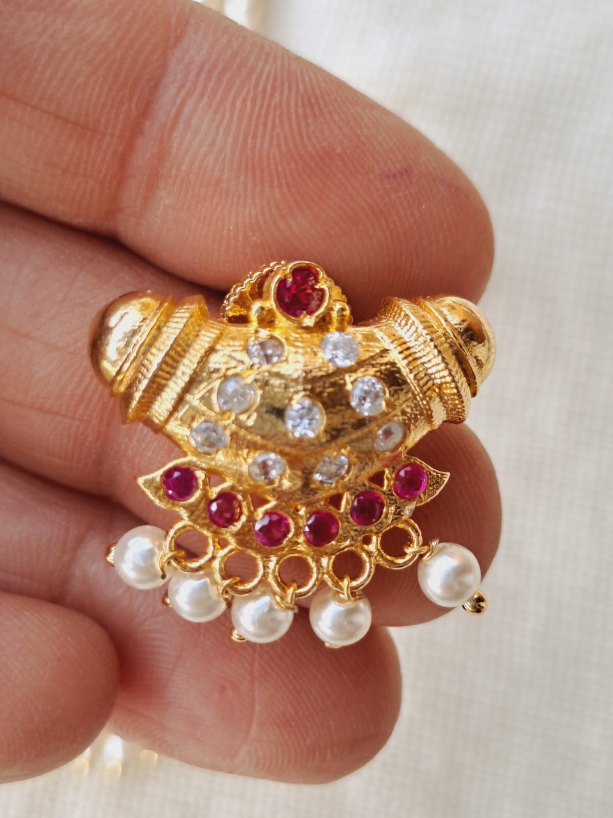 Ornate gold pendant with red gemstones and lustrous pearls from Mugdha Jewellery Store