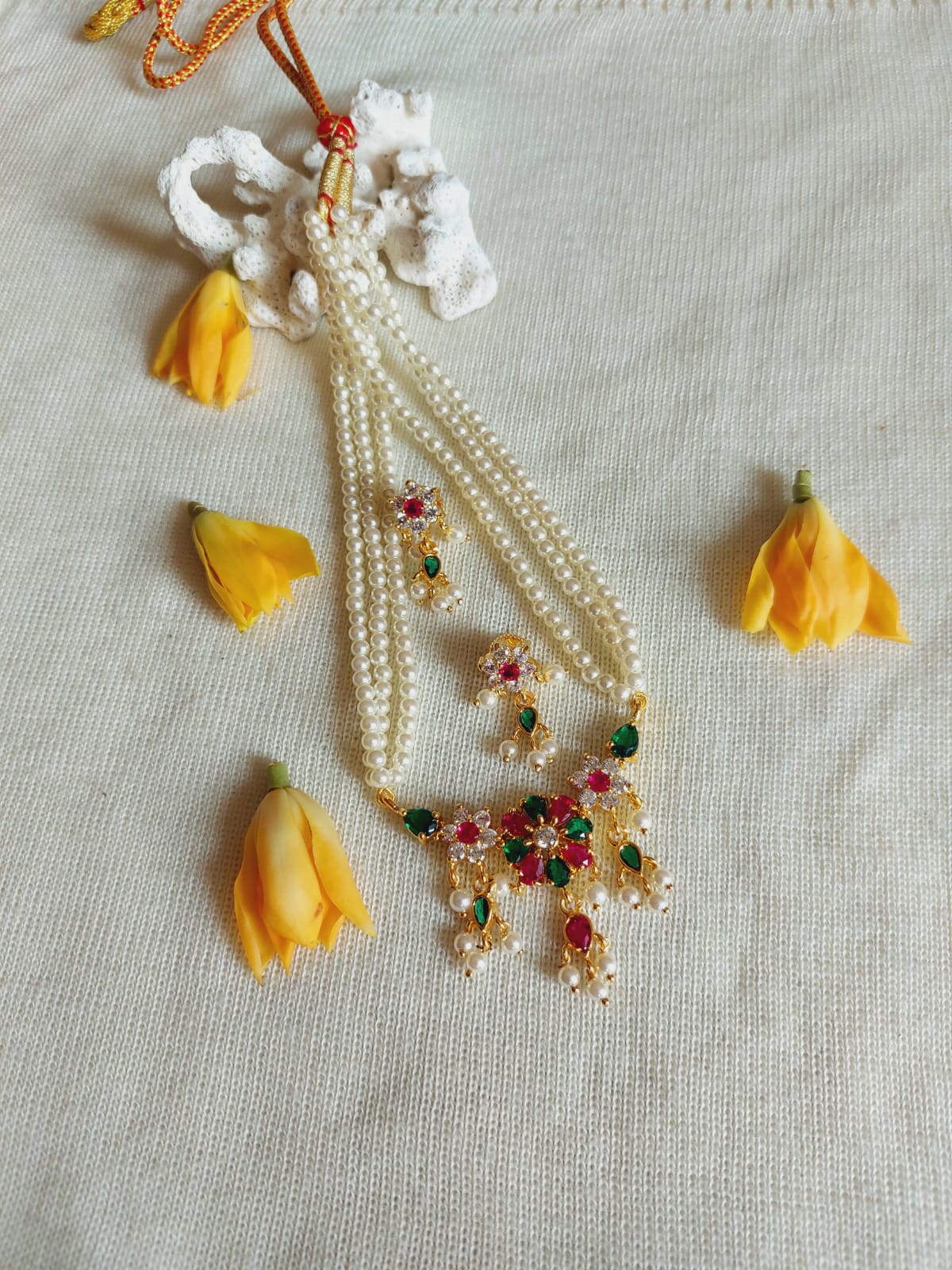 Elegant pearl and flower multi-colored tanmani necklace displayed on a light-colored fabric in the Mugdha Jewellery Store.