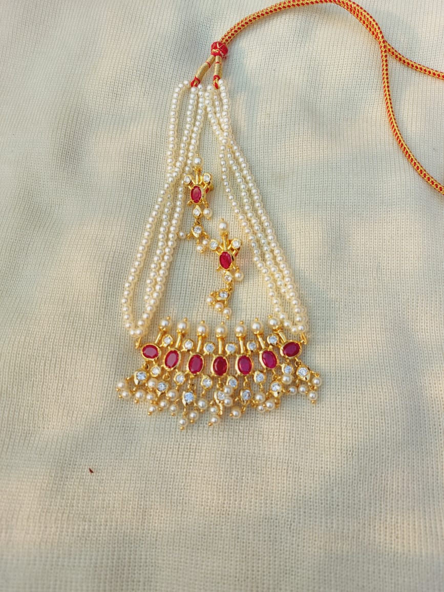 Opulent designer Maharani Tanmani necklace from Mugdha Jewellery Store, featuring intricate pearl strands, vibrant ruby gemstones, and a striking gold-toned chain.