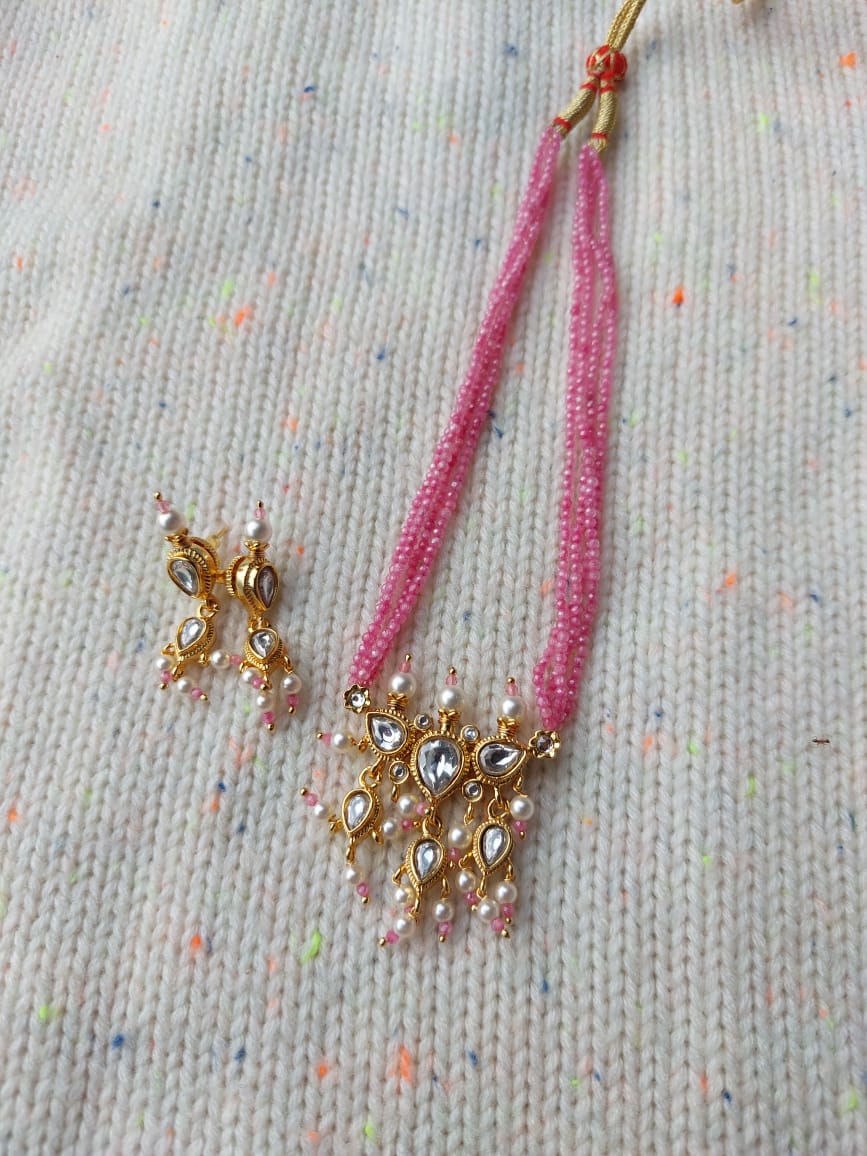 Premium Tanmani Collection - White Tanmani with Baby Pink Crystals
Elegant gold-tone jewelry set featuring a pink tanmani pendant with intricate crystal detailing