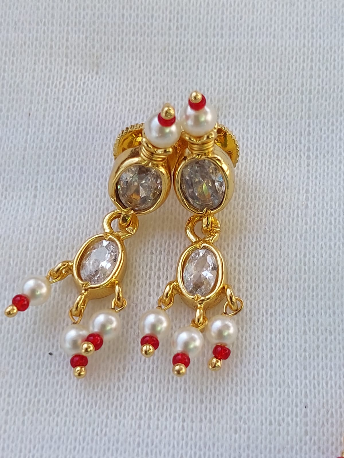 Elegant Maharani Tanmani Earrings - Gold-toned earrings with pearls, red beads, and sparkling oval gems, showcased on a white background.