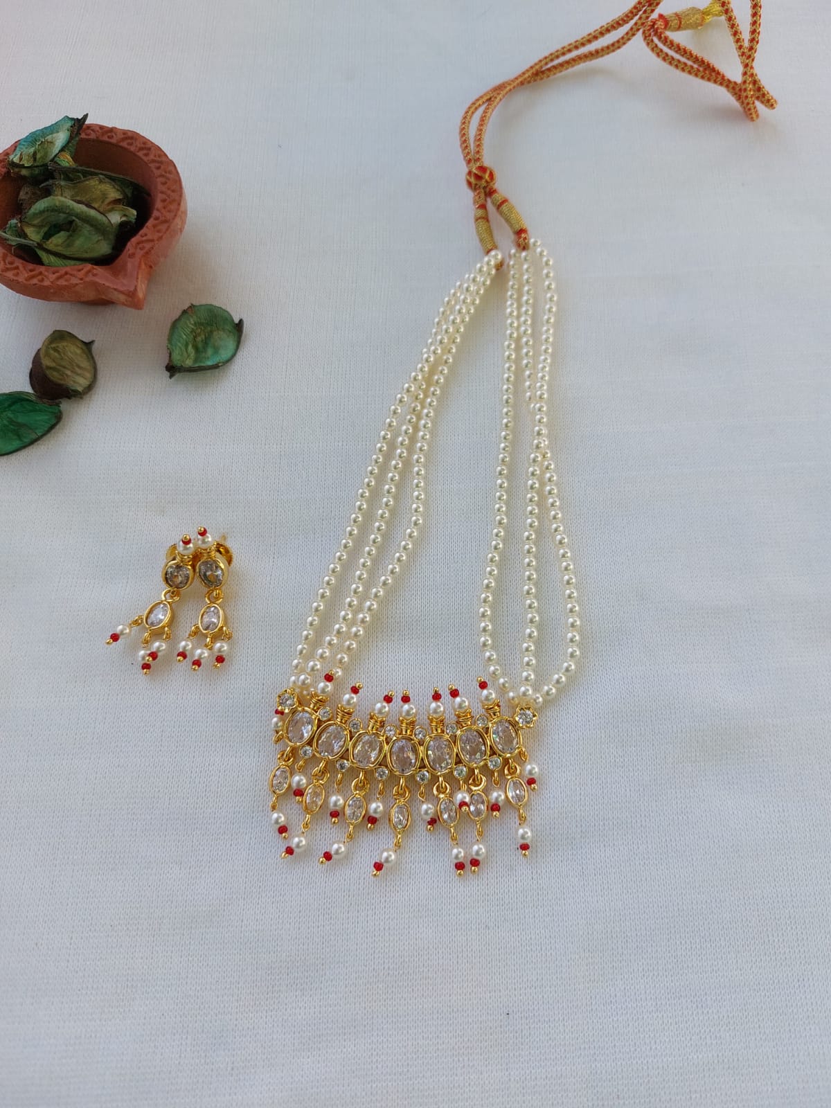 Elegant designer maharani tanmani white necklace with intricate pearl and gemstone detailing, displayed against a plain background with natural elements.
