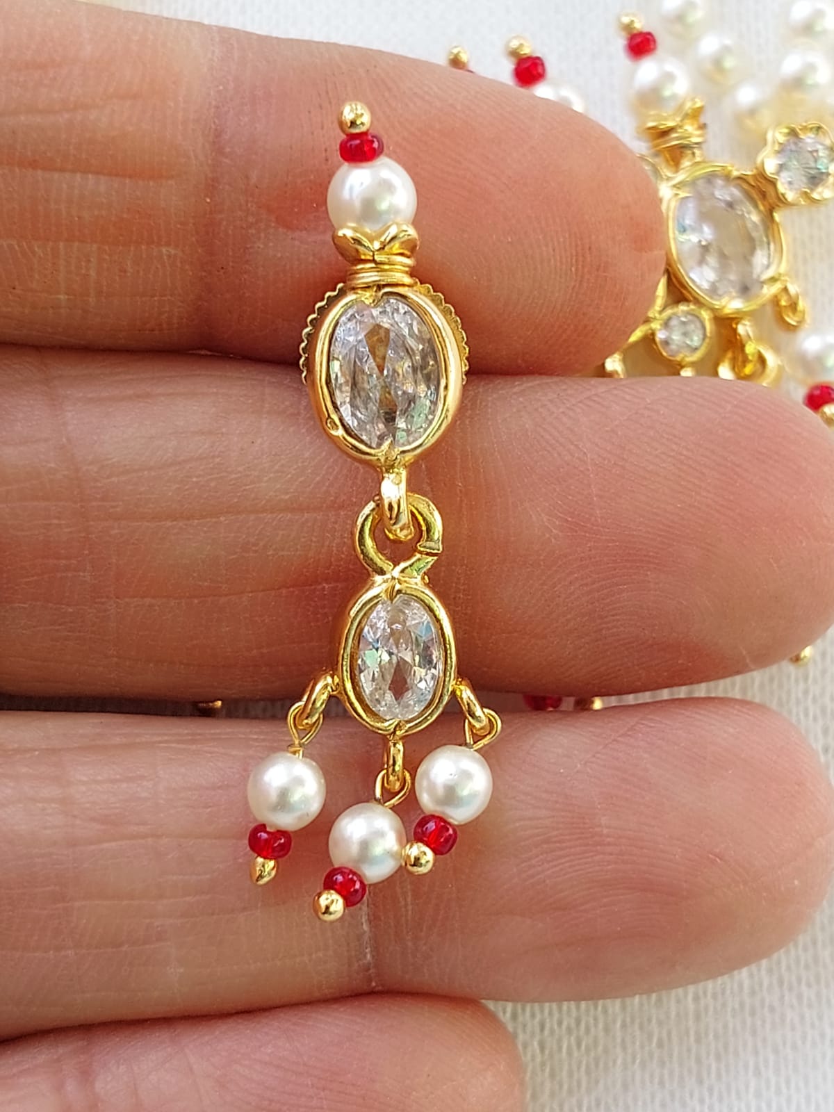 Elegant designer Maharani Tanmani white earring with oval-shaped crystal gems and delicate pearl accents on a gold-toned frame.