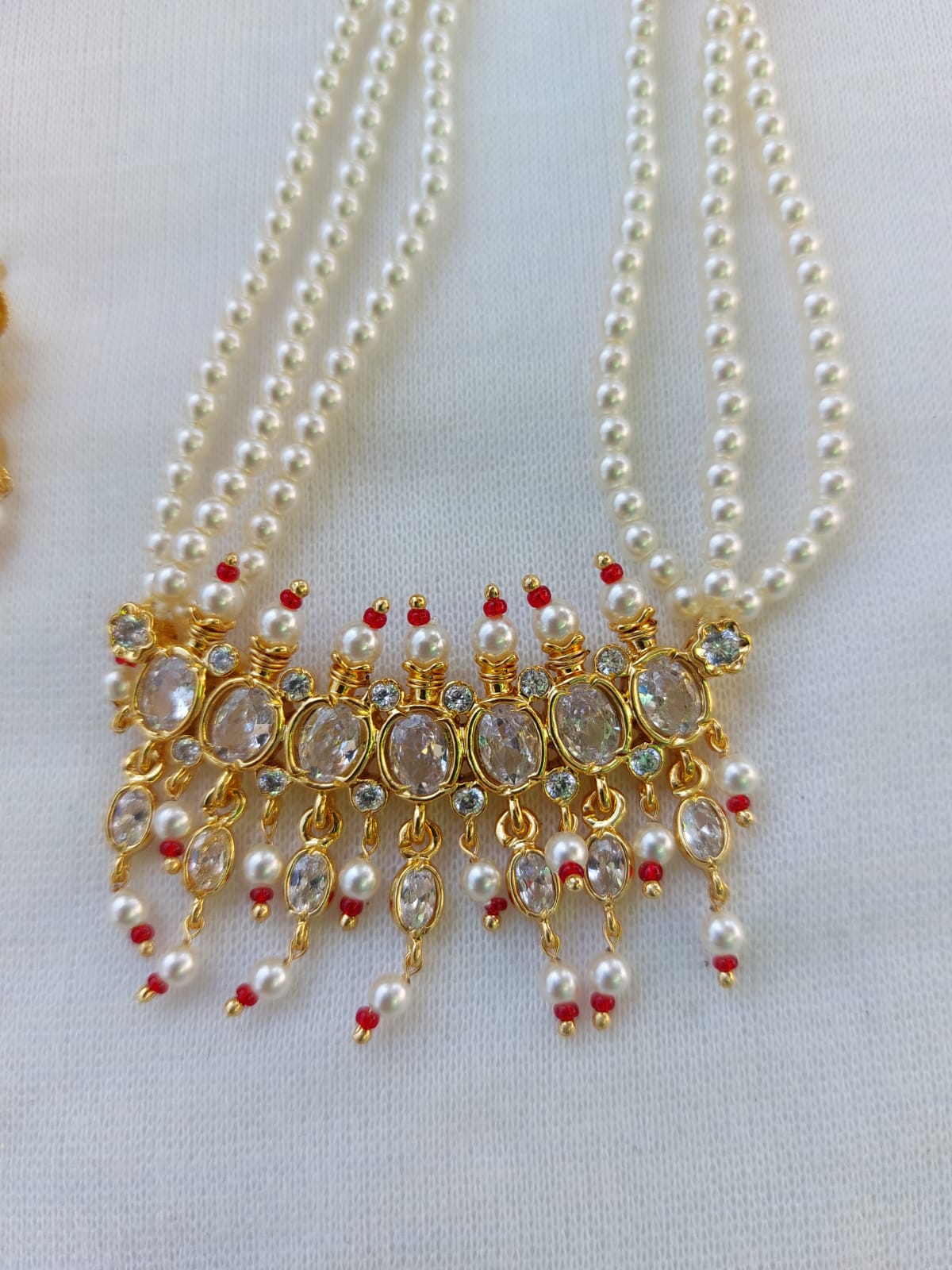 Magnificent pearl necklace with intricate golden pendant adorned with sparkling gems and dangling pearls, exuding elegance and sophistication.