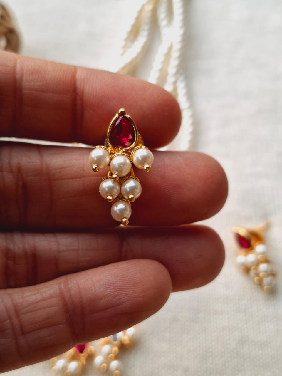 Dark Pink White Stone Draksha Tanmani 2 - Gold-toned pendant with red gemstone and white pearls, held in a hand against a light background