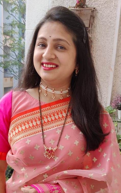 Vibrant pink saree with intricate golden patterns and jewelry, worn by woman with long dark hair and warm smile.