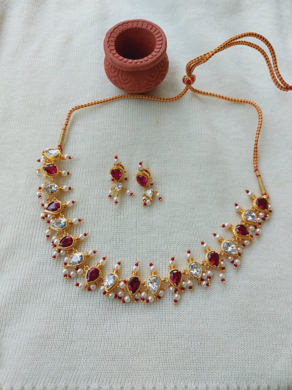 Elegant red AD tanmani necklace with sparkling gemstones and earrings set on light background