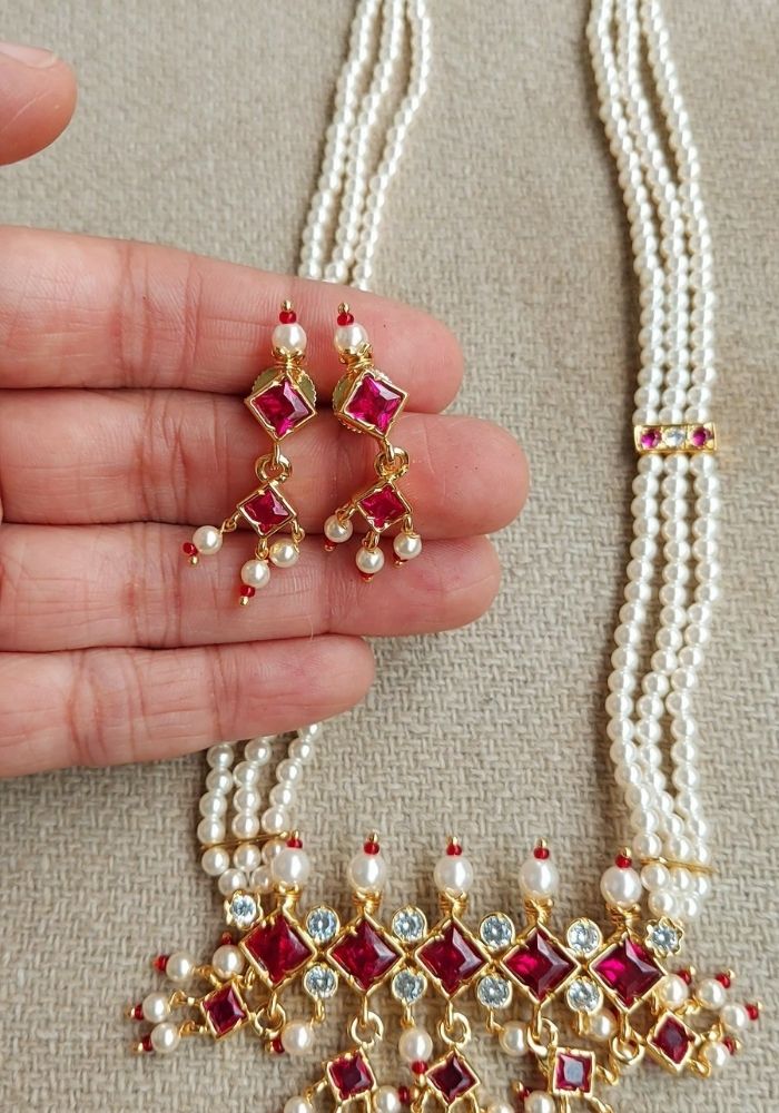 Elegant pearl necklace and earrings featuring red gemstones and intricate gold detailing from Mugdha Jewellery Store