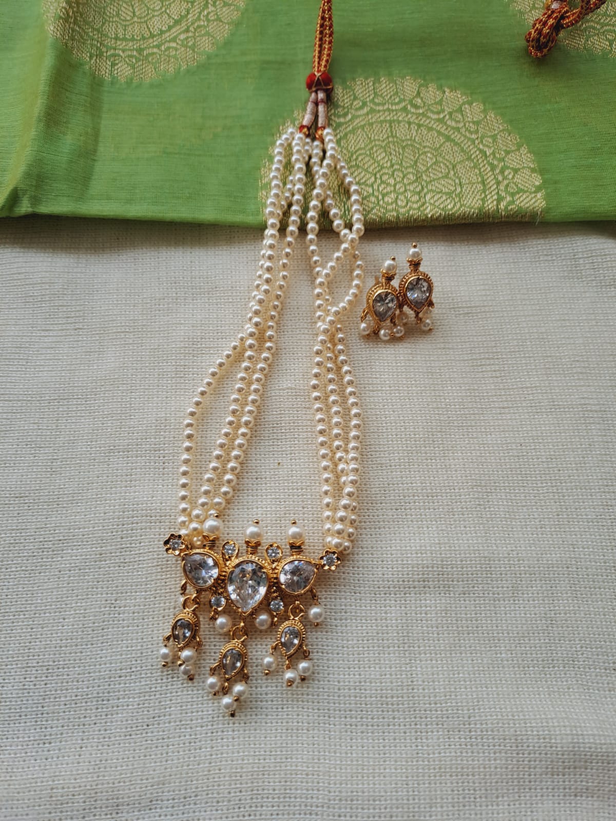 Elegant Pearl and Rhinestone Necklace Set - Triple-Strand Pearl Necklace with Sparkling Rhinestone Pendant on Green Patterned Fabric