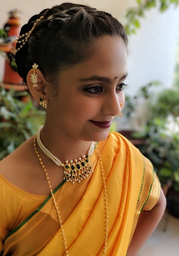 Elegant Indian woman in traditional yellow dress, intricate jewelry and braided hairstyle.