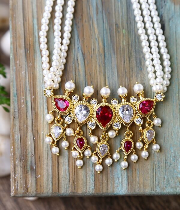 Elegant pearl and gem-encrusted necklace with a striking red, gold, and crystal pendant from the Mugdha Jewellery Store.