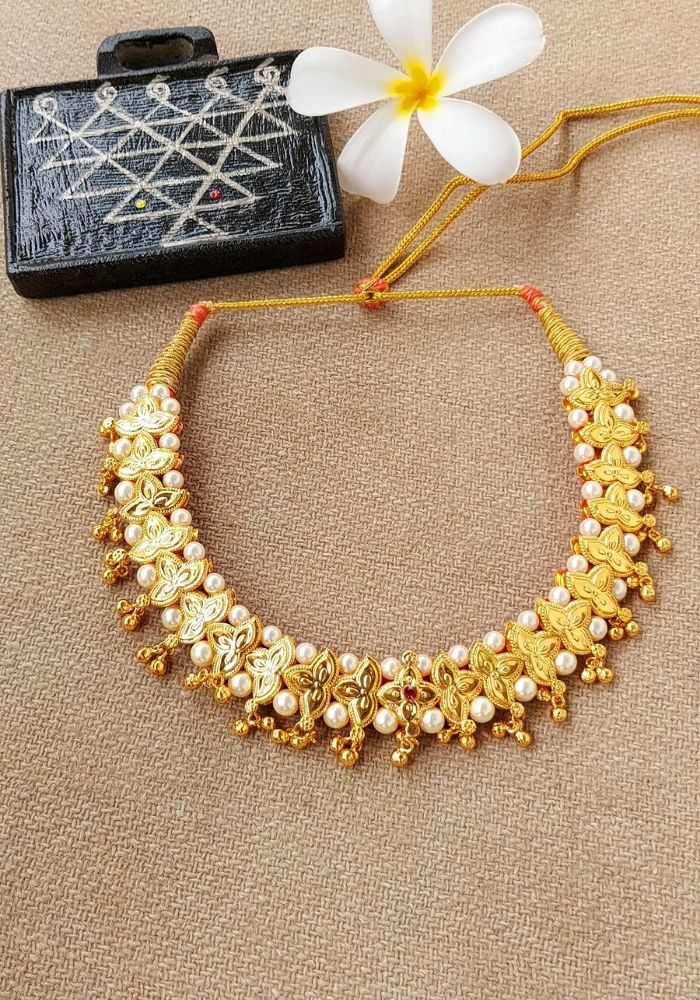 Traditional Belpan necklace from Mugdha Jewellery Store, featuring intricate golden beads and ornaments on a vibrant orange cord.